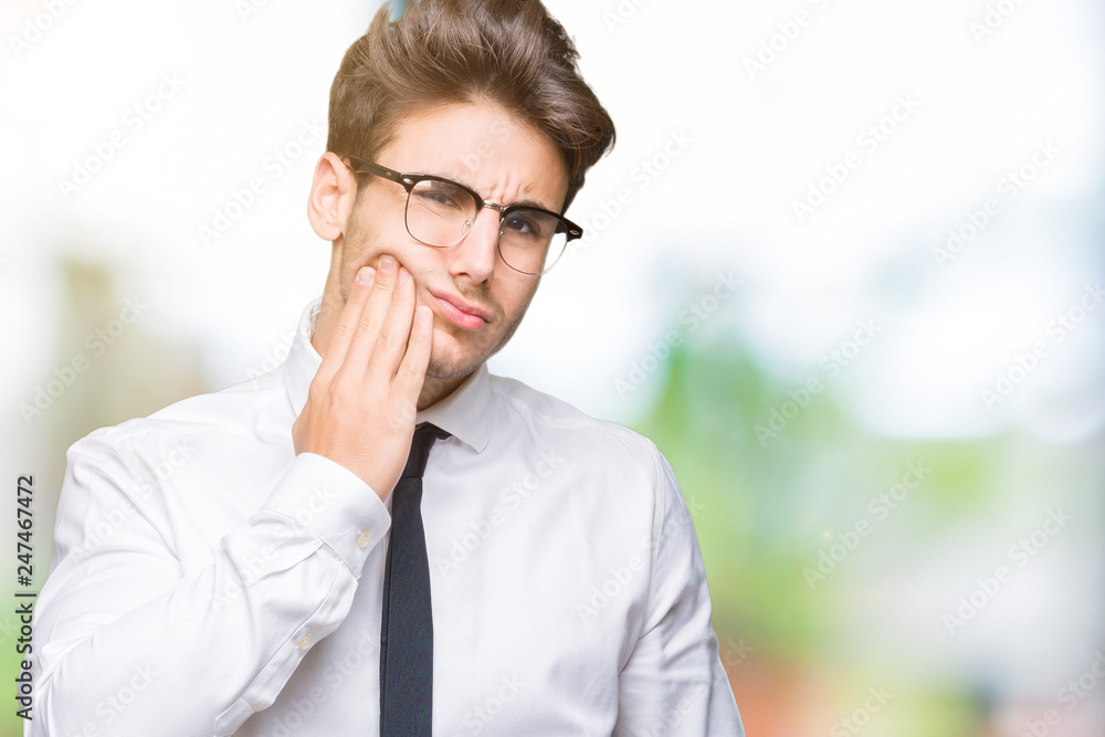 Young business man wearing glasses over isolated background touching mouth with hand with painful expression because of toothache or dental illness on teeth. Dentist concept. Young business man wearing glasses over isolated background touching mouth with hand with painful expression because of toothache or dental illness on teeth. Dentist concept.