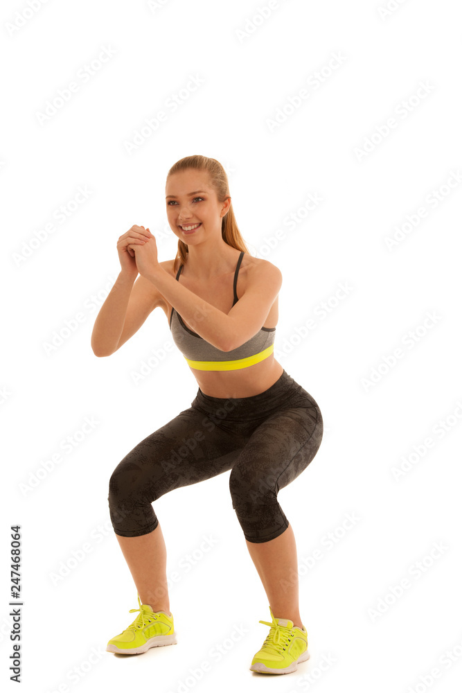 Beautiful young fit woman makes squats isolated over white background Beautiful young fit woman makes squats isolated over white background