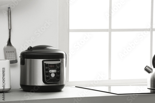Modern electric multi cooker on kitchen countertop. Space for text