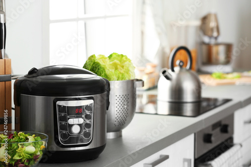 Modern electric multi cooker and food on kitchen countertop. Space for text