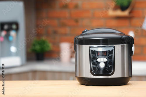 Modern electric multi cooker on table in kitchen. Space for text