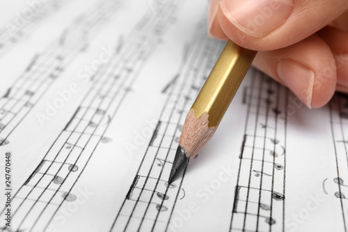 Bild auf Leinwand Woman writing music notes on sheet with pencil, closeup