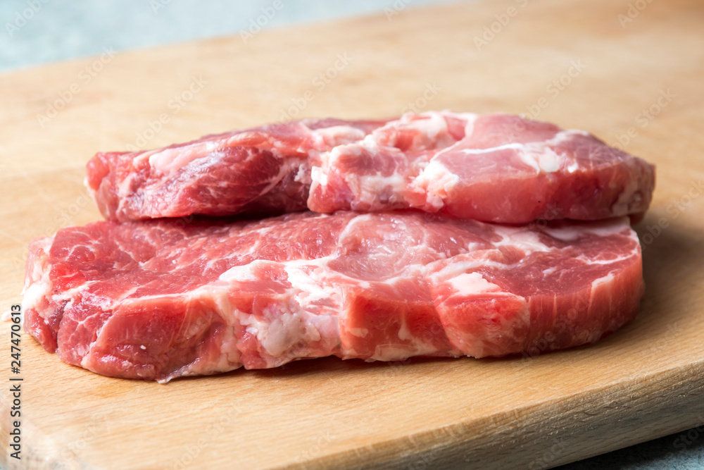 two pork meat steaks, on a cutting board