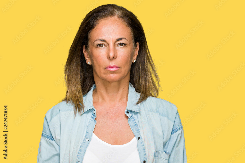 Obraz premium Middle age adult woman wearing casual denim shirt over isolated background with serious expression on face. Simple and natural looking at the camera.
