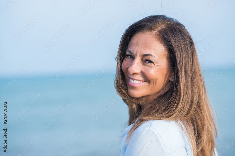 Beautiful middle age hispanic woman standing with smile on face at the ocean. Smiling confident and cheerful on a sunny day with sea view. .