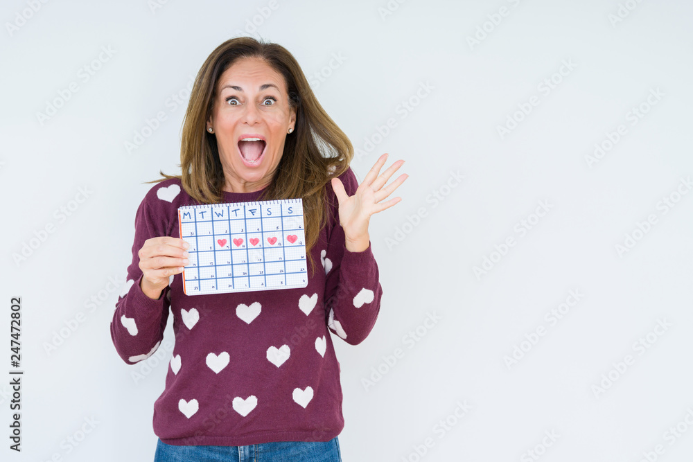Middle age woman holding menstruation calendar over isolated background very happy and excited, winner expression celebrating victory screaming with big smile and raised hands Middle age woman holding menstruation calendar over isolated background very happy and excited, winner expression celebrating victory screaming with big smile and raised hands