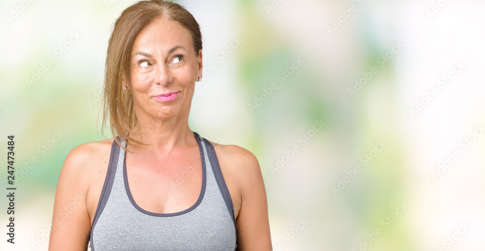 Beautiful middle age woman wearing sport clothes over isolated background smiling looking side and staring away thinking. Beautiful middle age woman wearing sport clothes over isolated background smiling looking side and staring away thinking.