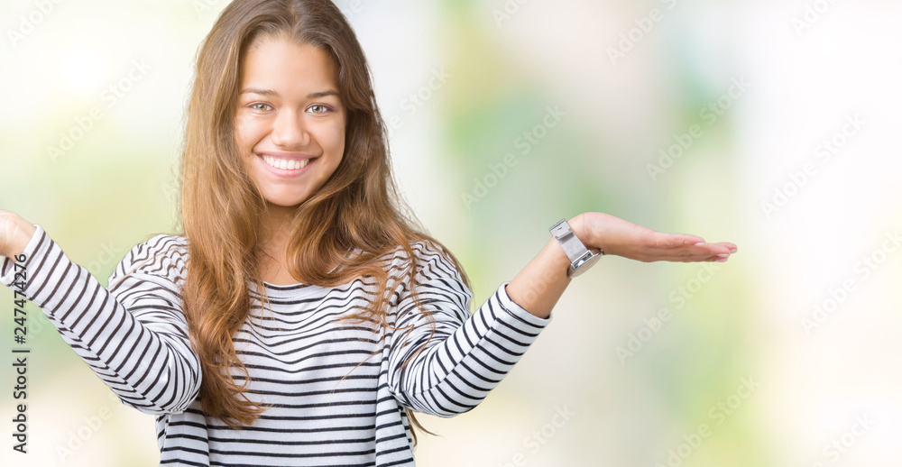 Young beautiful brunette woman wearing stripes sweater over isolated background Smiling showing both hands open palms, presenting and advertising comparison and balance Young beautiful brunette woman wearing stripes sweater over isolated background Smiling showing both hands open palms, presenting and advertising comparison and balance