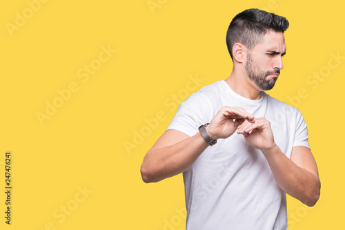 Young man wearing casual white t-shirt over isolated background disgusted expression, displeased and fearful doing disgust face because aversion reaction. With hands raised. Annoying concept.