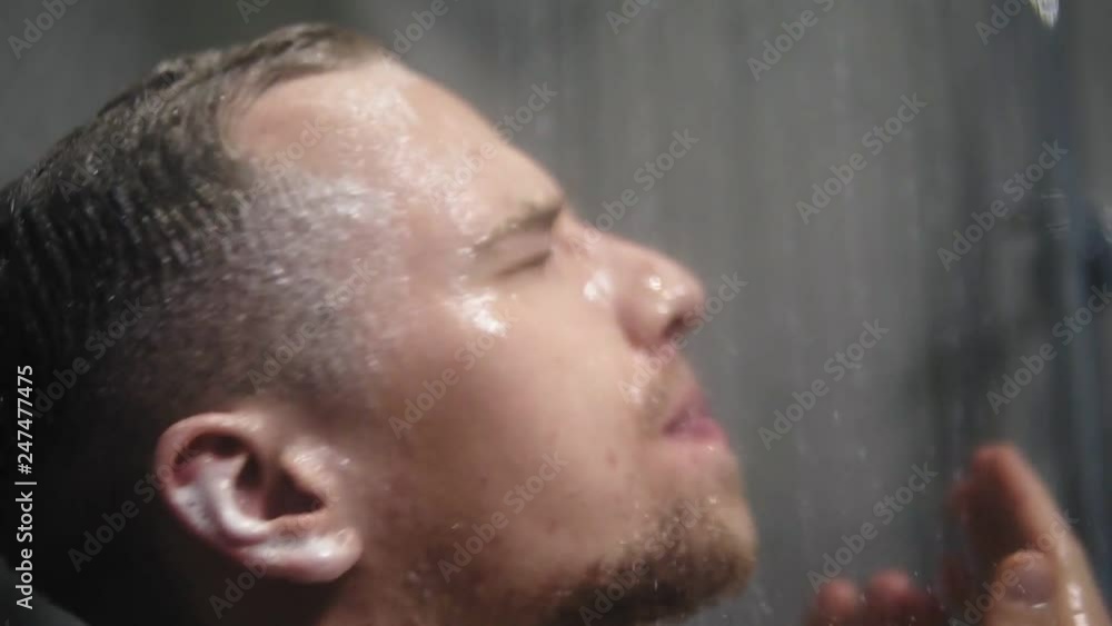 Young blonde man taking shower. Washing head with a hot water and shampoo. Close up Young blonde man taking shower. Washing head with a hot water and shampoo. Close up