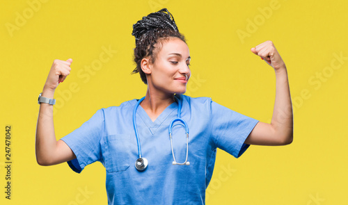 Young braided hair african american girl professional surgeon over isolated background showing arms muscles smiling proud. Fitness concept.