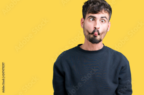 Young handsome man over isolated background making fish face with lips, crazy and comical gesture. Funny expression.