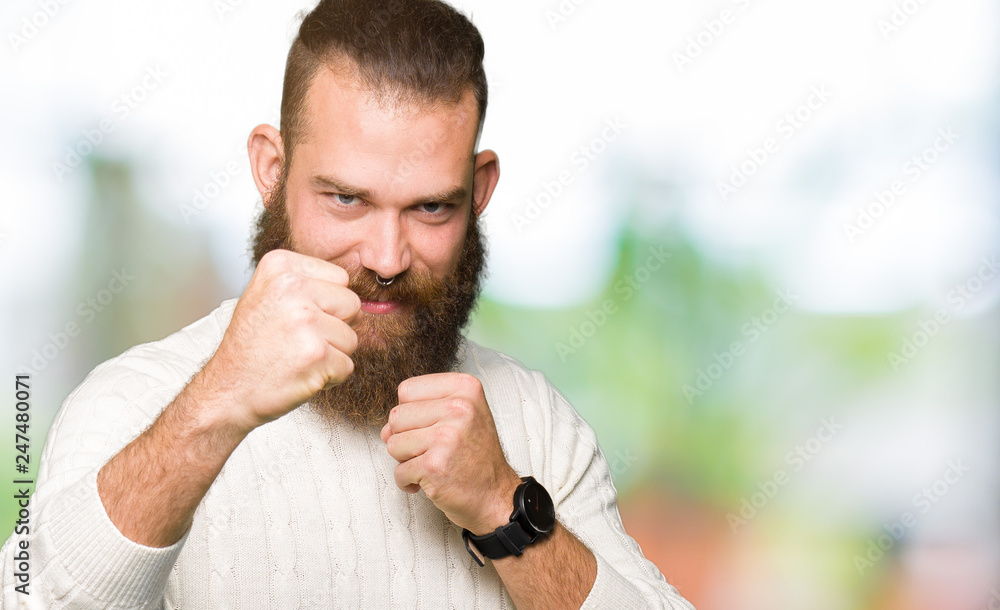 Young hipster man wearing winter sweater Punching fist to fight, aggressive and angry attack, threat and violence Young hipster man wearing winter sweater Punching fist to fight, aggressive and angry attack, threat and violence
