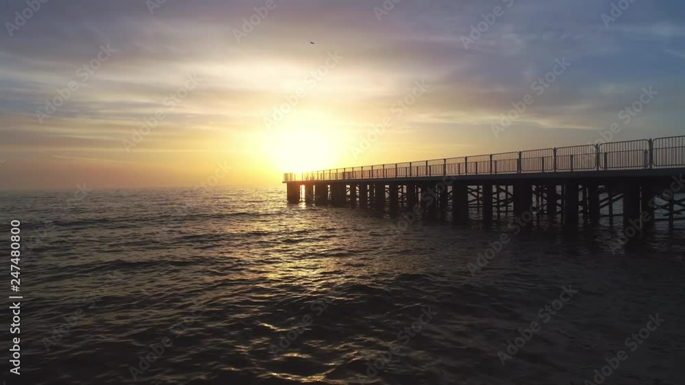 Aerial view over the old broken bridge in the sea and flying birds, sunrise shot Aerial view over the old broken bridge in the sea and flying birds, sunrise shot