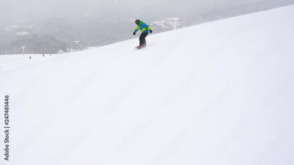 Extreme snowboarder riding fresh powder snow down the steep mountain slope Extreme snowboarder riding fresh powder snow down the steep mountain slope
