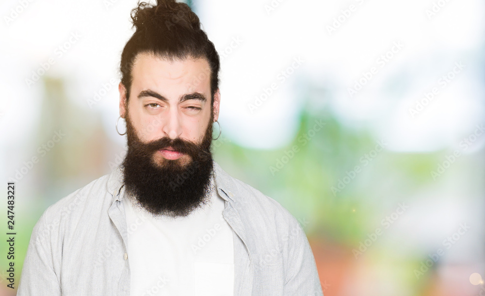 Young man with long hair, beard and earrings skeptic and nervous, frowning  upset because of problem. Negative person. Stock Photo | Adobe Stock