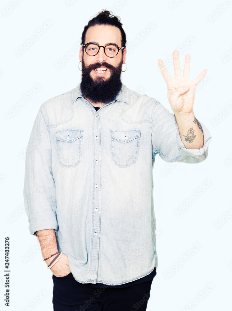 Young hipster man with long hair and beard wearing glasses showing and pointing up with fingers number four while smiling confident and happy. Young hipster man with long hair and beard wearing glasses showing and pointing up with fingers number four while smiling confident and happy.
