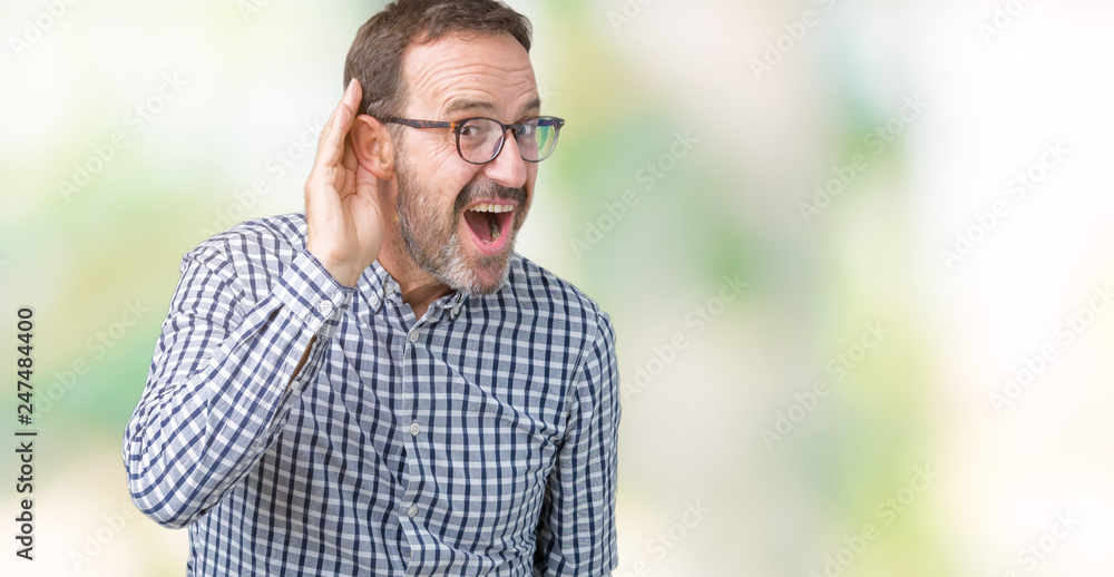 Handsome middle age elegant senior business man wearing glasses over isolated background smiling with hand over ear listening an hearing to rumor or gossip. Deafness concept. Handsome middle age elegant senior business man wearing glasses over isolated background smiling with hand over ear listening an hearing to rumor or gossip. Deafness concept.