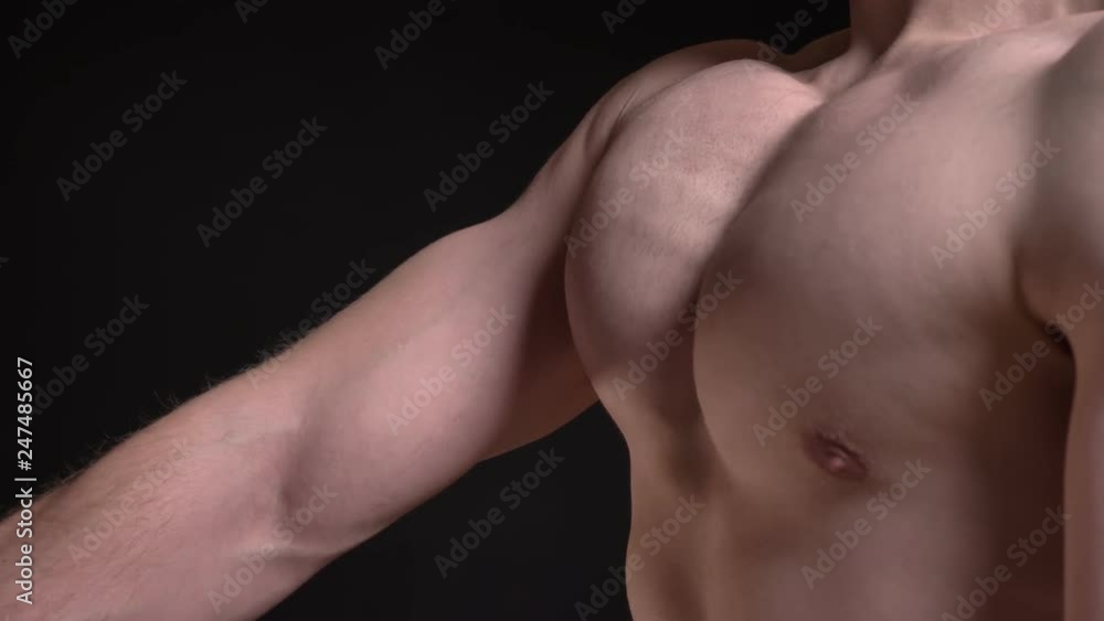 Portrait in profile of male breast moving and showing muscles into camera on black background. Portrait in profile of male breast moving and showing muscles into camera on black background.