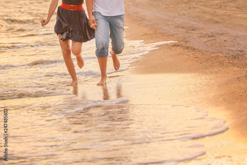 couple in love runs barefoot on the sea along the surf at sunset. honeymoon, valentine, happiness and love. with copy space for text