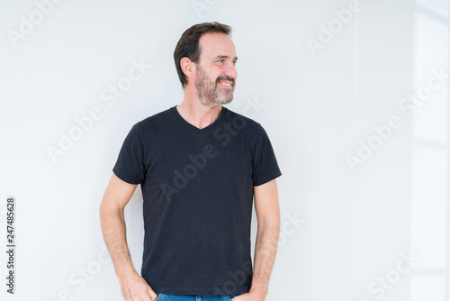 Senior man over isolated background looking away to side with smile on face, natural expression. Laughing confident. © Krakenimages.com
