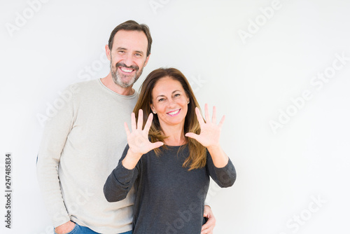Beautiful middle age couple in love over isolated background showing and pointing up with fingers number ten while smiling confident and happy.