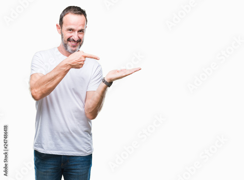 Middle age hoary senior man wearing white t-shirt over isolated background amazed and smiling to the camera while presenting with hand and pointing with finger.