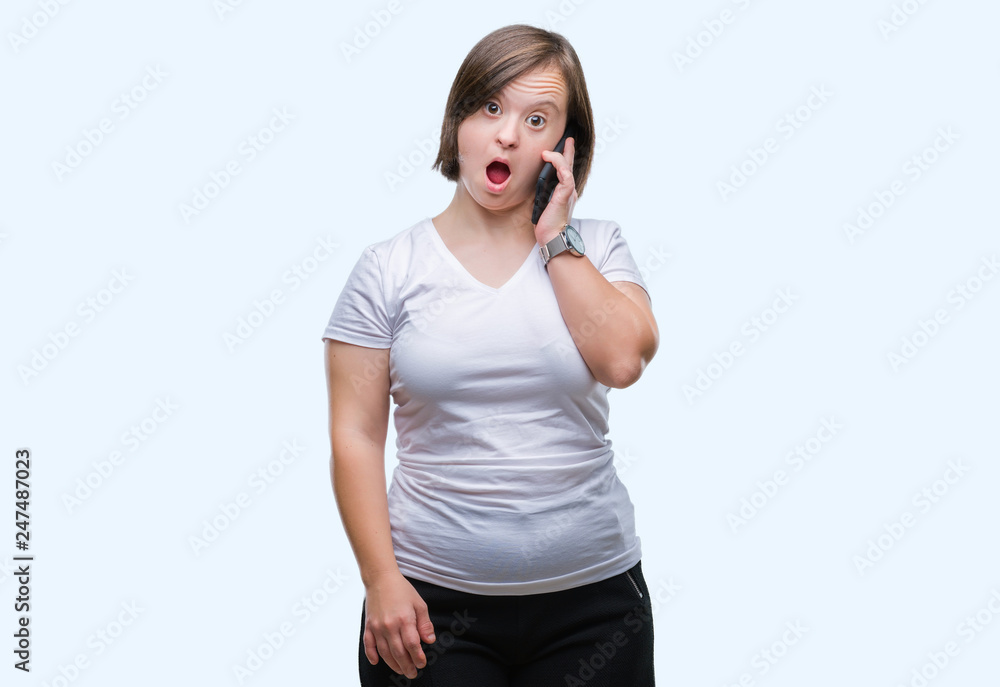 Young adult woman with down syndrome taking using smartphone over isolated background scared in shock with a surprise face, afraid and excited with fear expression Young adult woman with down syndrome taking using smartphone over isolated background scared in shock with a surprise face, afraid and excited with fear expression