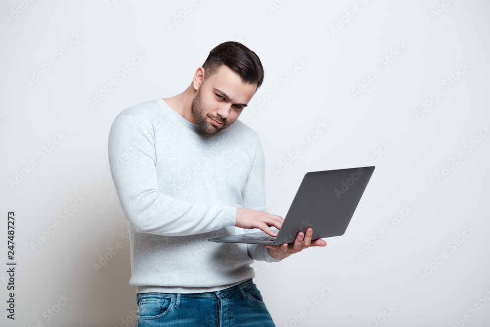 Portrait of young man typing on laptop keyboard over white background. Portrait of young man typing on laptop keyboard over white background.