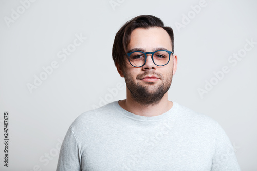 Portrait of young man wearing blue glasses over white background. © Lalandrew