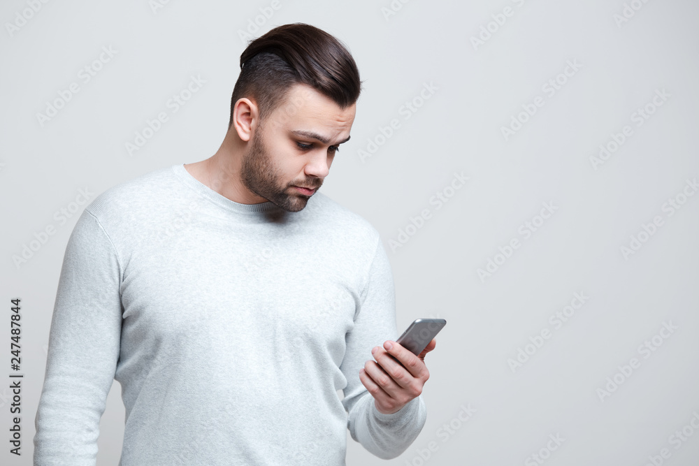 Portrait of young man looking in smartphone over white background. Portrait of young man looking in smartphone over white background.