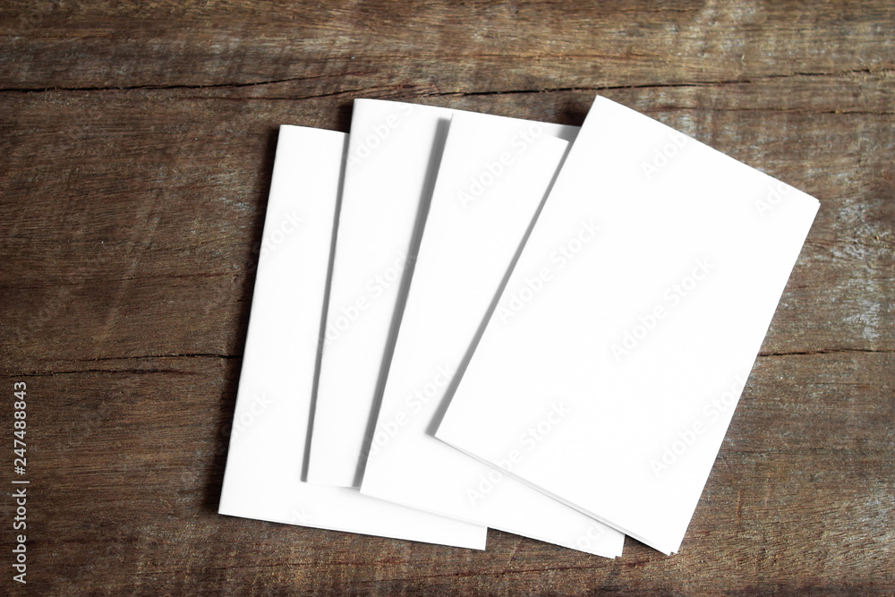 Blank portrait mock-up paper. brochure magazine isolated on brown wooden table, changeable background / white paper isolated on wood Blank portrait mock-up paper. brochure magazine isolated on brown wooden table, changeable background / white paper isolated on wood
