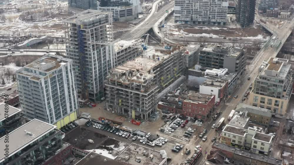 winter aerial moving around condo construction site in busy urban downtown with highway in background winter aerial moving around condo construction site in busy urban downtown with highway in background