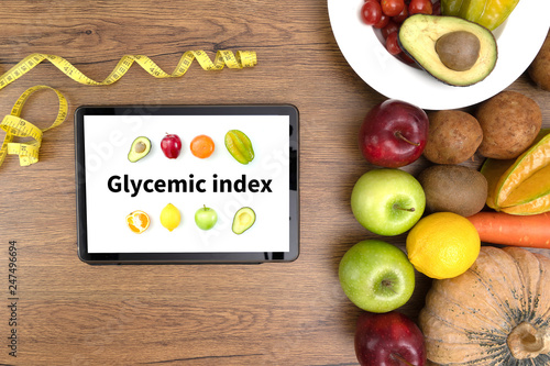 Glycemic index Fitness and weight loss concept, dumbbells, white scale, fruit and tape measure on a wooden table, top view