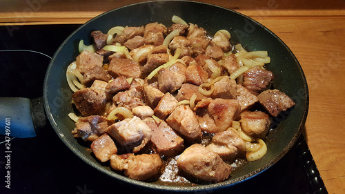 pan with large pieces of pork, fried with onions