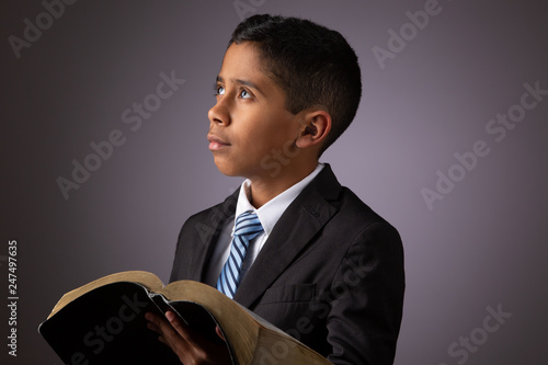 Little Hispanic Boy  Looking Away while Holding the Holy Scriptures, The Word of God, The Bible