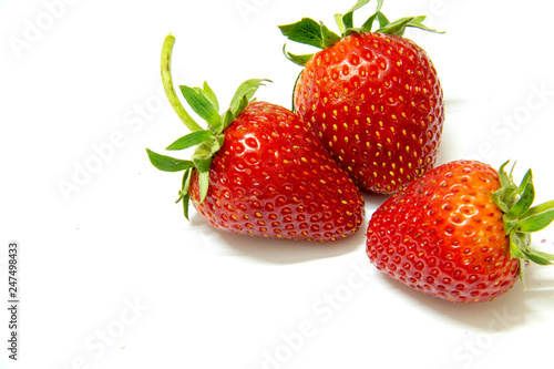 Three strawberries close up on white background.