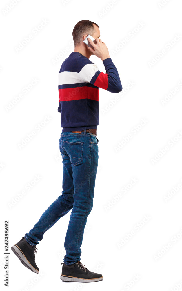 a side view of man walking with a mobile phone. a side view of man walking with a mobile phone.