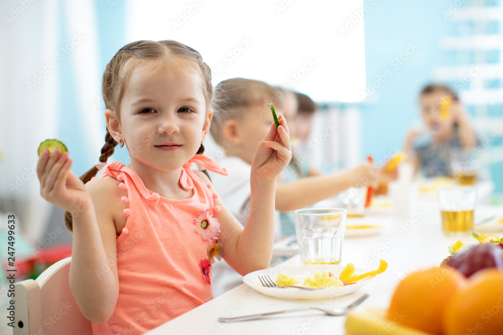 Adorable kid girl eating vegetables in kindergarten Adorable kid girl eating vegetables in kindergarten