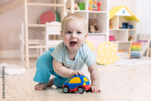 funny baby boy playing toy in nursery or kindergarten