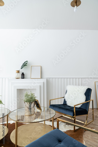 Cozy living room corner with gold and blue velvet fabric armchair and gold mirror coffee table in modern classic style with natural light setting scene / studio shot / interior design decoration
