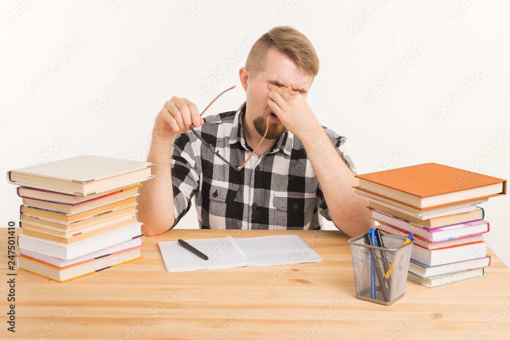 Knowledge, student and education concept - Tired guy sits at the table and makes notes in a notebook Knowledge, student and education concept - Tired guy sits at the table and makes notes in a notebook