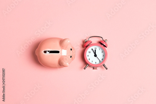 Foto Piggy bank and classic alarm clock on pink background