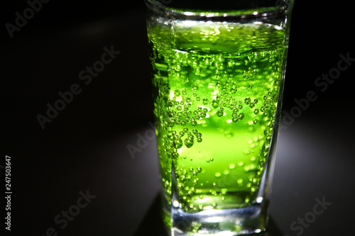 bright lucent green fizzy drink (lemonade, cocktail) with many small bubbles in dark closeup