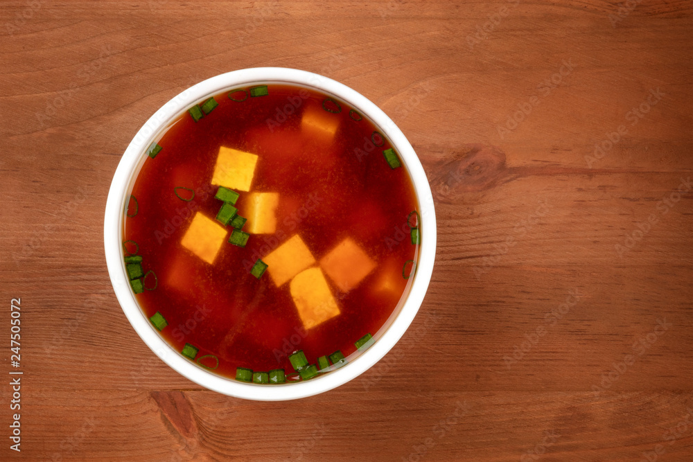 A bowl of miso soup with tofu and scallions, shot from the top on a dark rustic background with copy space A bowl of miso soup with tofu and scallions, shot from the top on a dark rustic background with copy space