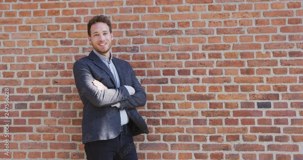Happy Confident Manager Smiling businessman standing with arms crossed in pride. Confident male executive is wearing smart casual clothing leaning against brick wall. Happy Confident Manager Smiling businessman standing with arms crossed in pride. Confident male executive is wearing smart casual clothing leaning against brick wall.