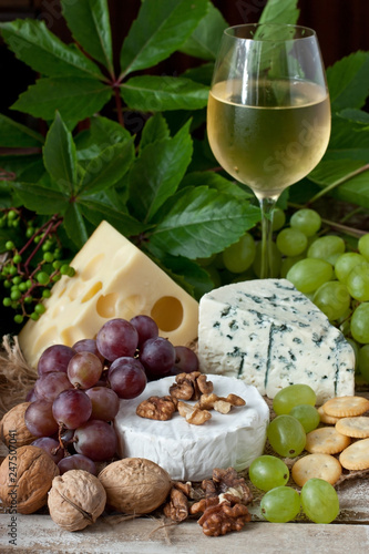 Various types of cheese, wine glass and fruits