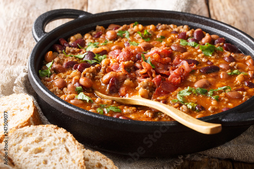 Delicious cowboy stew of beans with ground beef, bacon in a spicy sauce closeup in a bowl. horizontal