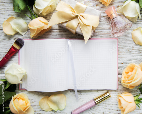 Notebook, Roses and cosmetic on a old wooden table photo