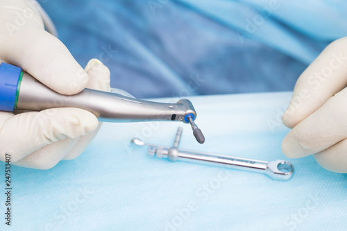Close-up dental implant in the hands of a dentist. An implantation surgery is underway.